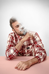 Image showing Handsome hipster man smoking cigarette at home. Man looking upwards and enjoying spending free time.