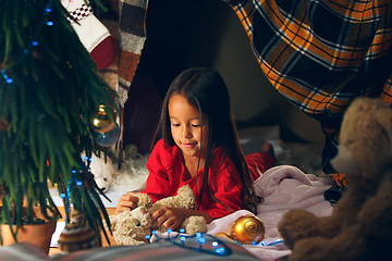 Image showing christmas, holidays and childhood concept - happy girl in red clothes decorating natural fir tree