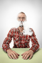 Image showing Handsome hipster man smoking cigarette at home. Man looking upwards and enjoying spending free time.