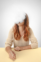 Image showing Tranquil woman sitting and smoking resting at the table. Cloud of smoke covering her face. Copy space