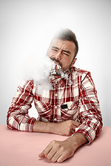 Image showing Handsome hipster man smoking cigarette at home. Man looking upwards and enjoying spending free time.