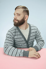 Image showing Serious business man sitting at a table on a blue background