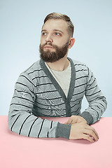 Image showing Serious business man sitting at a table on a blue background