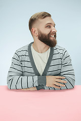 Image showing The happy smiling businessman sitting at a table on a blue background