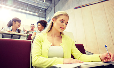 Image showing student girl writing to notebook at lecture hall