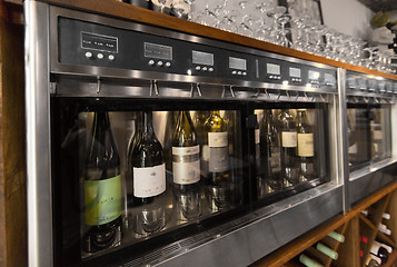 Image showing close up of wine bottles in dispenser at bar