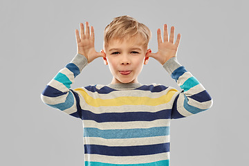 Image showing little boy in red t-shirt making big ears by hands