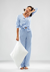 Image showing happy sleepy woman in blue pajama holding pillow