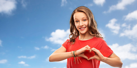 Image showing smiling teenage girl in red making hand heart