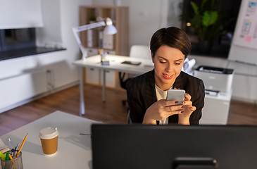 Image showing businesswoman using smartphone at night office