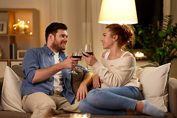 Image showing happy couple drinking red wine at home in evening