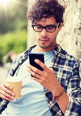 Image showing man with smartphone drinking coffee on city street