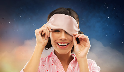 Image showing happy young woman peeking from under sleeping mask