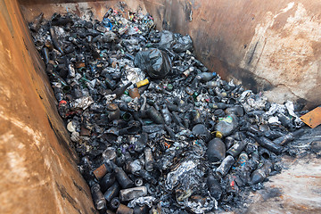 Image showing In a large garbage tank lie charred glass and allumines and bottles