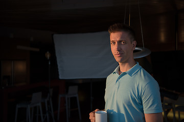 Image showing young man enjoying evening coffee by the window