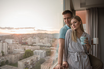 Image showing young couple enjoying evening coffee by the window