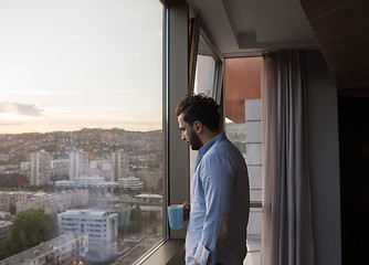 Image showing young man enjoying evening coffee by the window