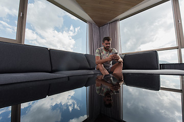 Image showing young casual man using a mobile phone at home