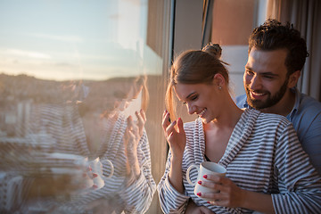 Image showing young couple enjoying evening coffee by the window