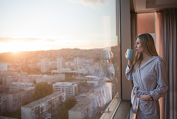 Image showing young woman enjoying evening coffee by the window