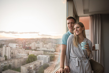 Image showing young couple enjoying evening coffee by the window