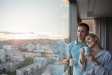 Image showing young couple enjoying evening coffee by the window