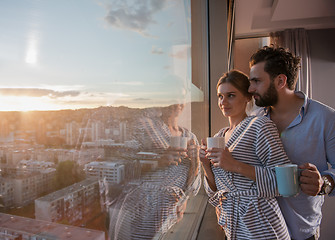 Image showing young couple enjoying evening coffee by the window