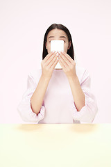 Image showing The business woman sitting with mobile phone against pink background.