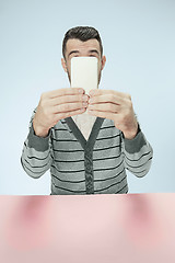 Image showing Surprised business man talking on phone sitting at the table