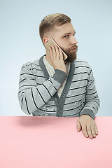 Image showing Surprised business man talking on phone sitting at the table