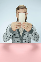 Image showing Surprised business man talking on phone sitting at the table