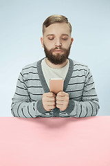 Image showing Serious business man with mobile phone sitting at the table