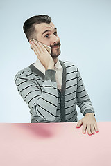 Image showing Surprised business man talking on phone sitting at the table