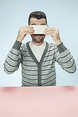 Image showing Surprised business man talking on phone sitting at the table