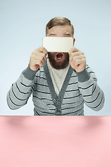 Image showing Surprised business man talking on phone sitting at the table