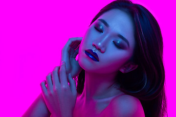 Image showing High Fashion model woman in colorful bright lights posing in studio