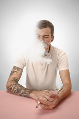 Image showing Handsome hipster man smoking cigarette at home. Man looking upwards and enjoying spending free time.