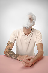 Image showing Handsome hipster man smoking cigarette at home. Man looking upwards and enjoying spending free time.