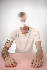 Image showing Handsome hipster man smoking cigarette at home. Man looking upwards and enjoying spending free time.