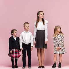 Image showing Cute stylish children on pink studio background. The beautiful teen girls and boy standing together