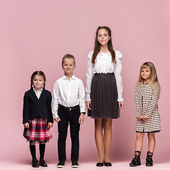 Image showing Cute stylish children on pink studio background. The beautiful teen girls and boy standing together