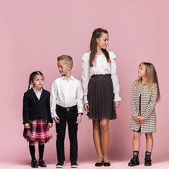 Image showing Cute stylish children on pink studio background. The beautiful teen girls and boy standing together