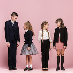 Image showing Cute stylish children on pink studio background. The beautiful teen girls and boy standing together