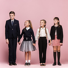 Image showing Cute stylish children on pink studio background. The beautiful teen girls and boy standing together