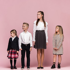 Image showing Cute stylish children on pink studio background. The beautiful teen girls and boy standing together