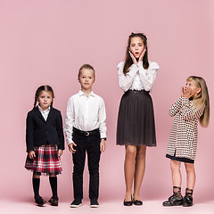 Image showing Cute stylish children on pink studio background. The beautiful teen girls and boy standing together