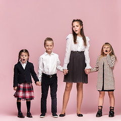 Image showing Cute stylish children on pink studio background. The beautiful teen girls and boy standing together