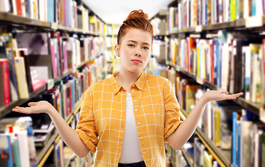 Image showing sad red haired student girl shrugging at library