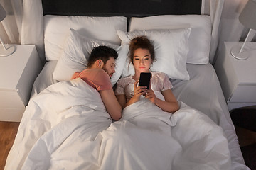 Image showing woman using smartphone while boyfriend is sleeping