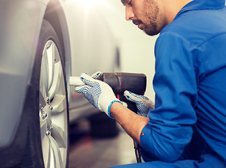 Image showing mechanic with screwdriver changing car tire